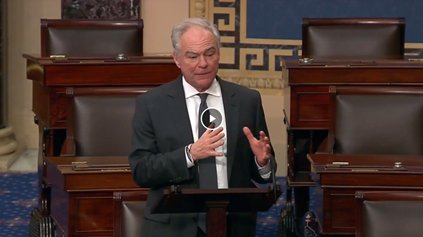 Senator Kaine speaking on Senate floor in front of lectern.