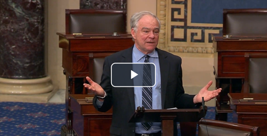 Senator Kaine speaking on Senate floor in front of lectern with hands raised.